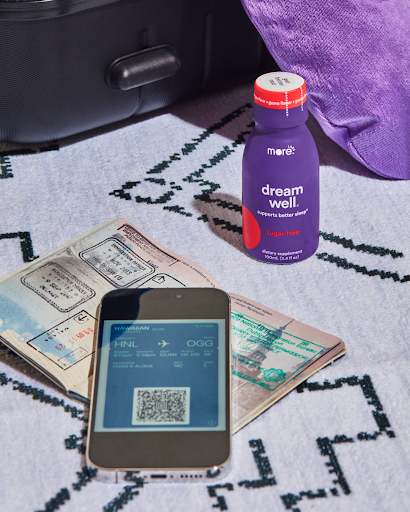 More Labs Dream Well sleep support drink placed beside passport, phone, and boarding pass for travel hydration and jet lag support.