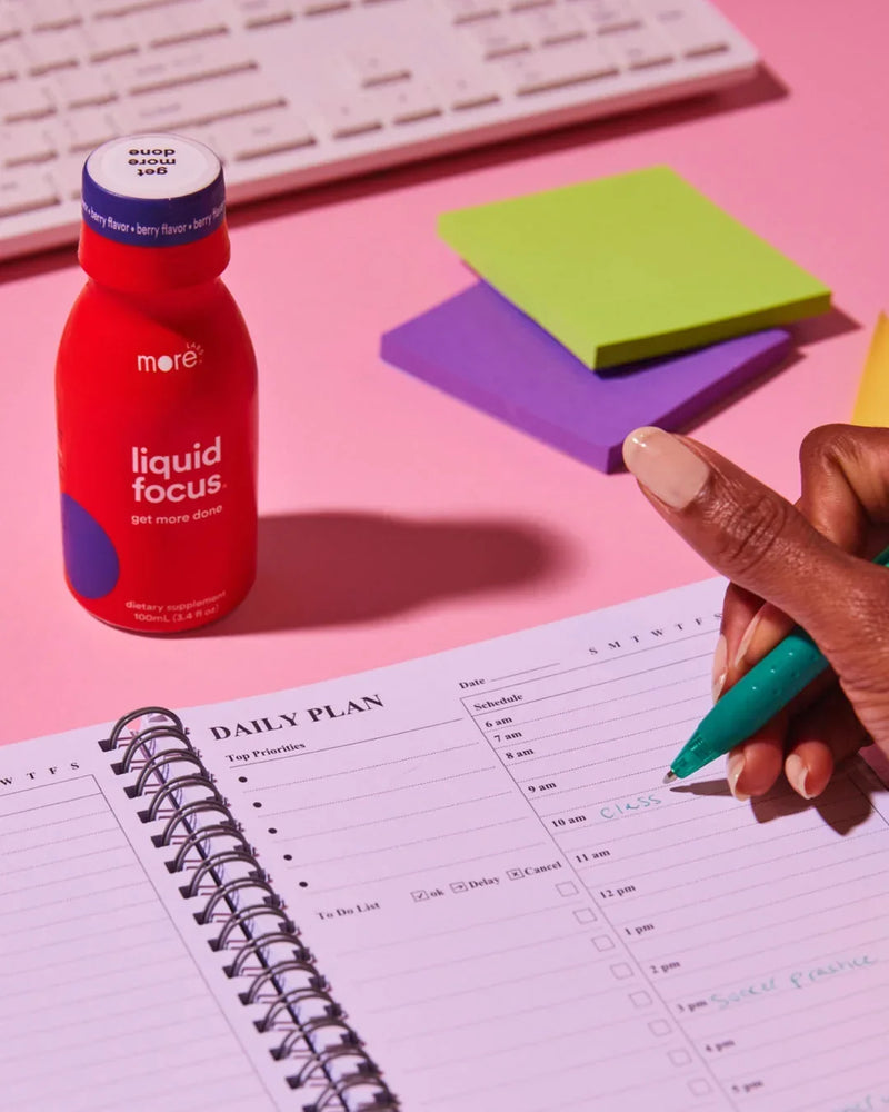 More Labs Liquid Focus bottle beside a daily planner and workspace setup for productivity.