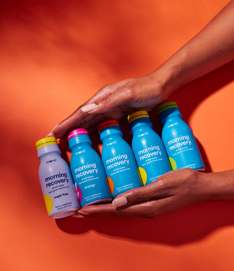 More Labs Morning Recovery bottles arranged in hands against a bold orange backdrop.