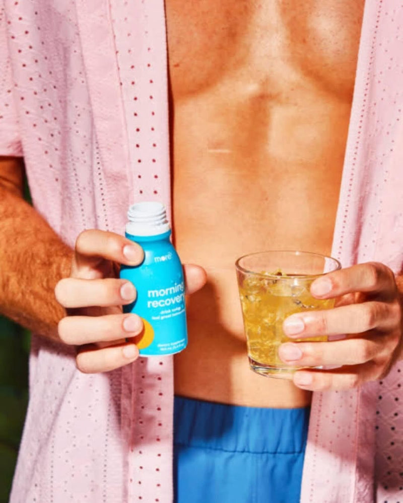 A man holding a drink and a More Labs Morning Recovery bottle.