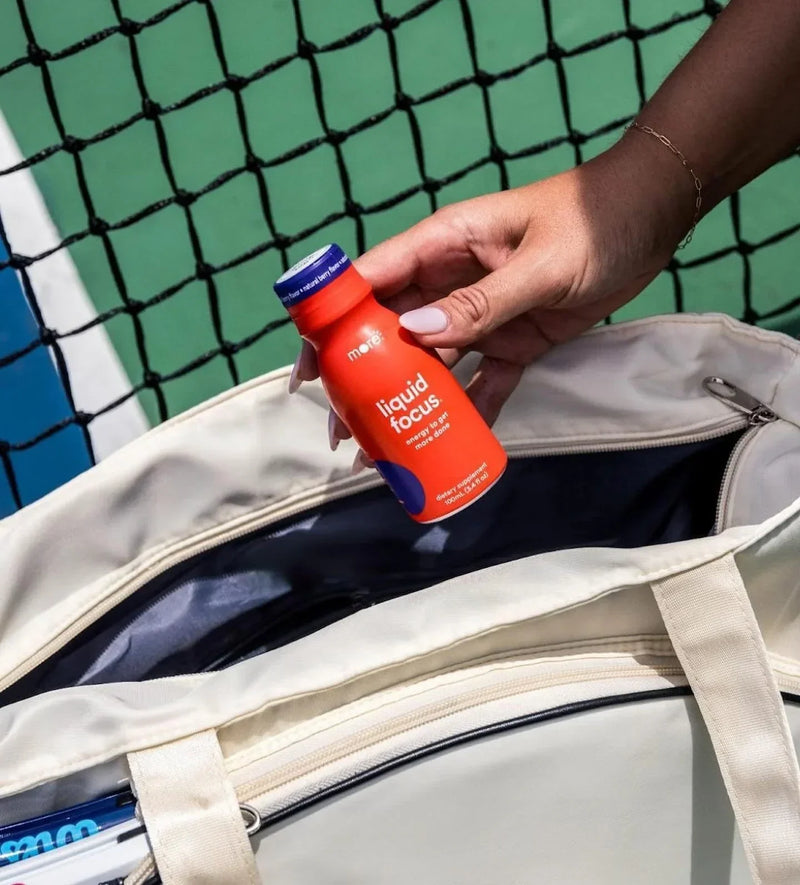 More Labs Liquid Focus bottle placed in a tote bag with a hand preparing for an active day.