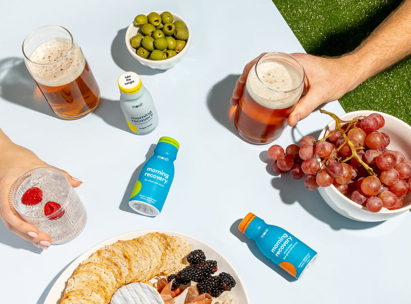 More Labs Morning Recovery bottle on a table with drinks, fruit, and snacks during a casual gathering.