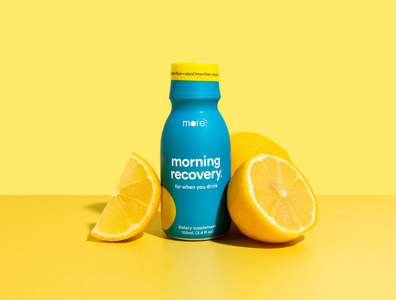 More Labs Morning Recovery dietary supplement bottle with two citrus fruits on a clean yellow background.