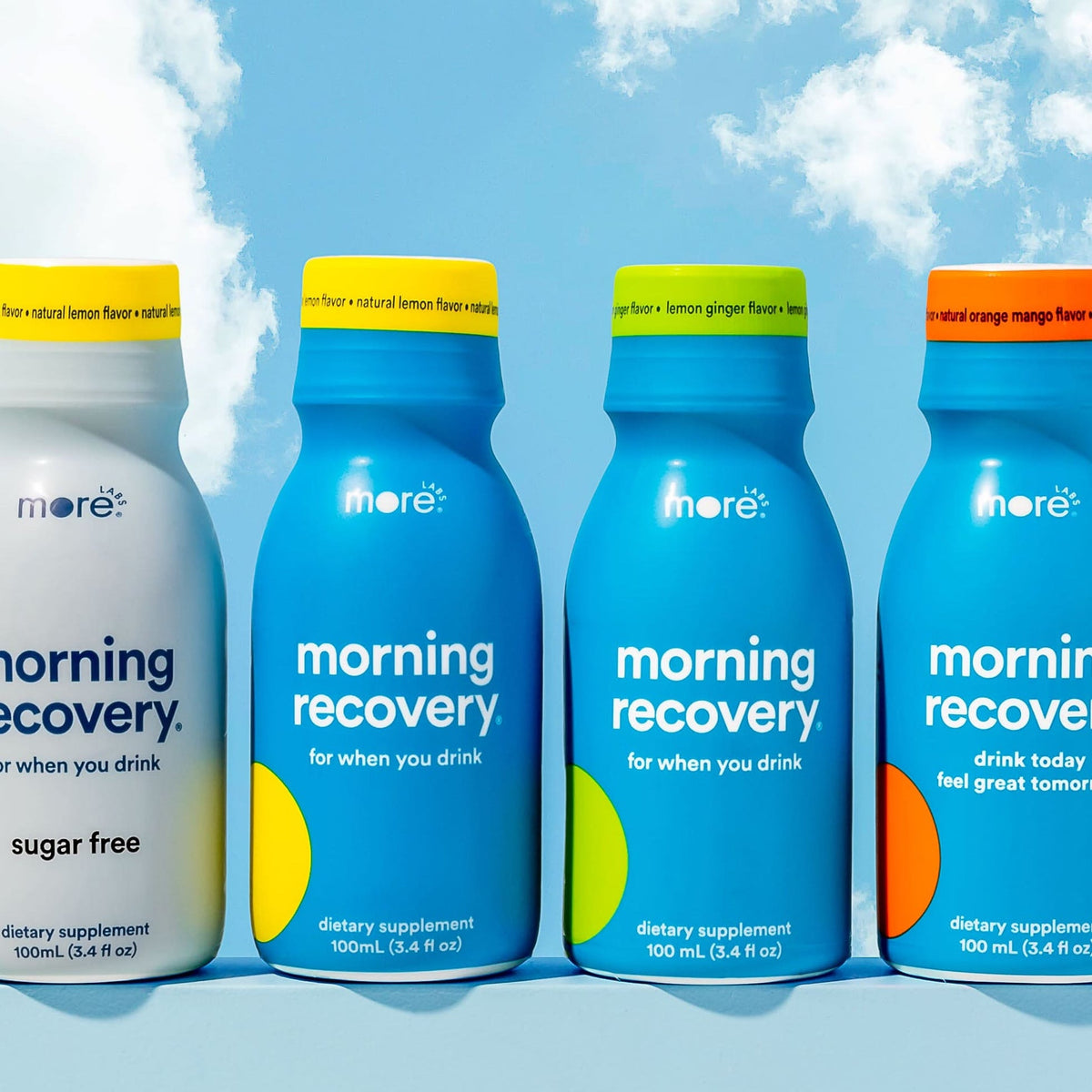 More Labs Morning Recovery bottles in assorted flavors against a blue sky background.
