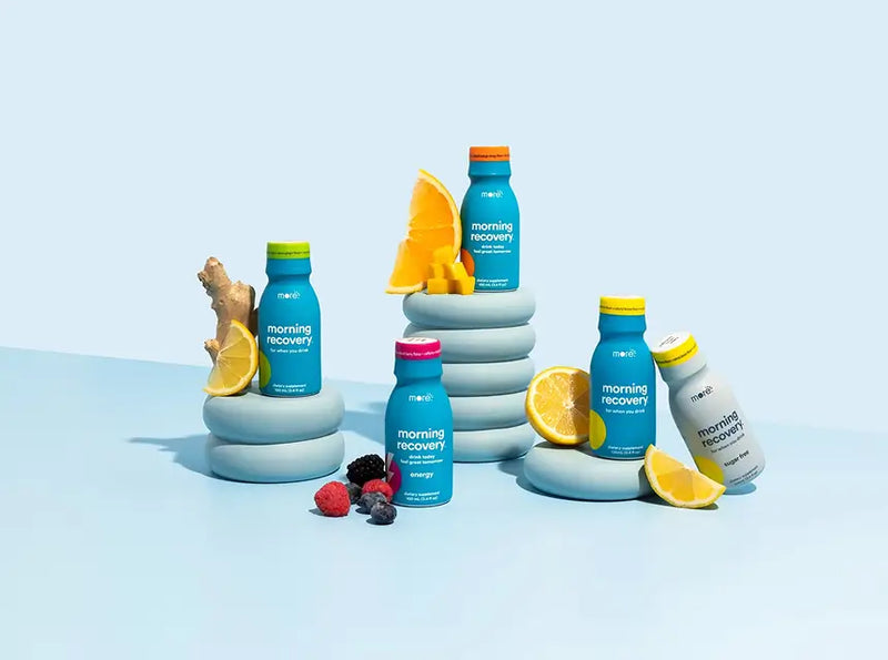 Collection of More Labs wellness drink bottles with citrus and berry ingredients on a light blue background.
