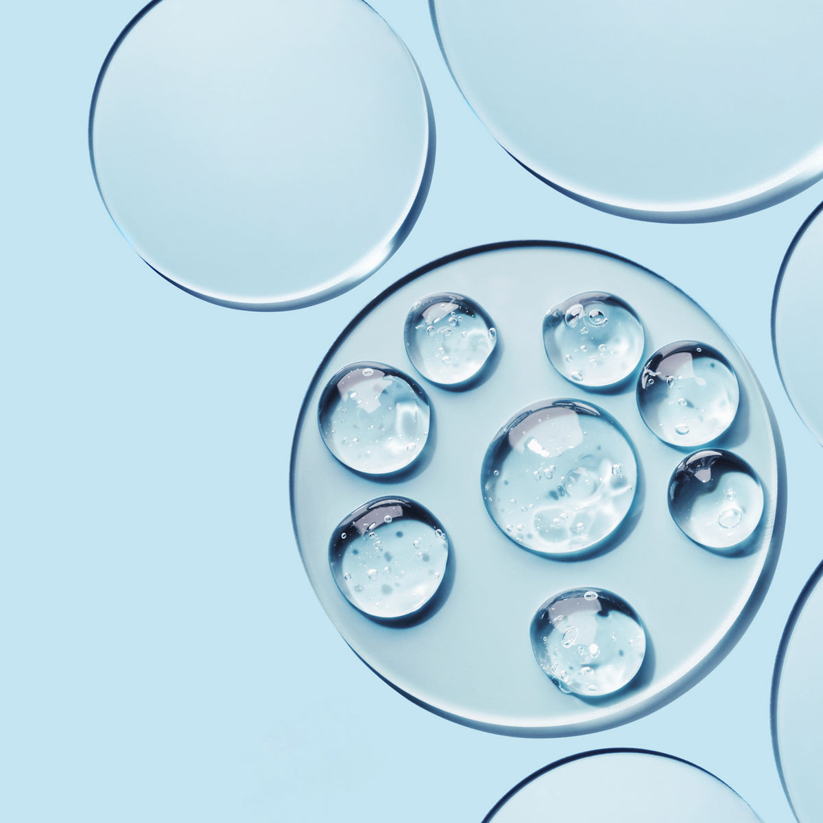 Abstract skincare-inspired background with clear liquid bubbles on a light blue surface.
